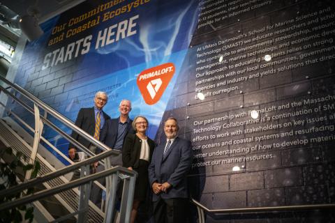 Pat Larkin, Deputy Director, Massachusetts Technology Collaborative, Lieutenant Governor Karyn Polito, Chancellor Mark Fuller, Jean VanderGheynst, Dean of Engineering and interim Dean of SMAST, and Mike Joyce '85, PrimaLoft CEO posing in front of a mural outside the new lab